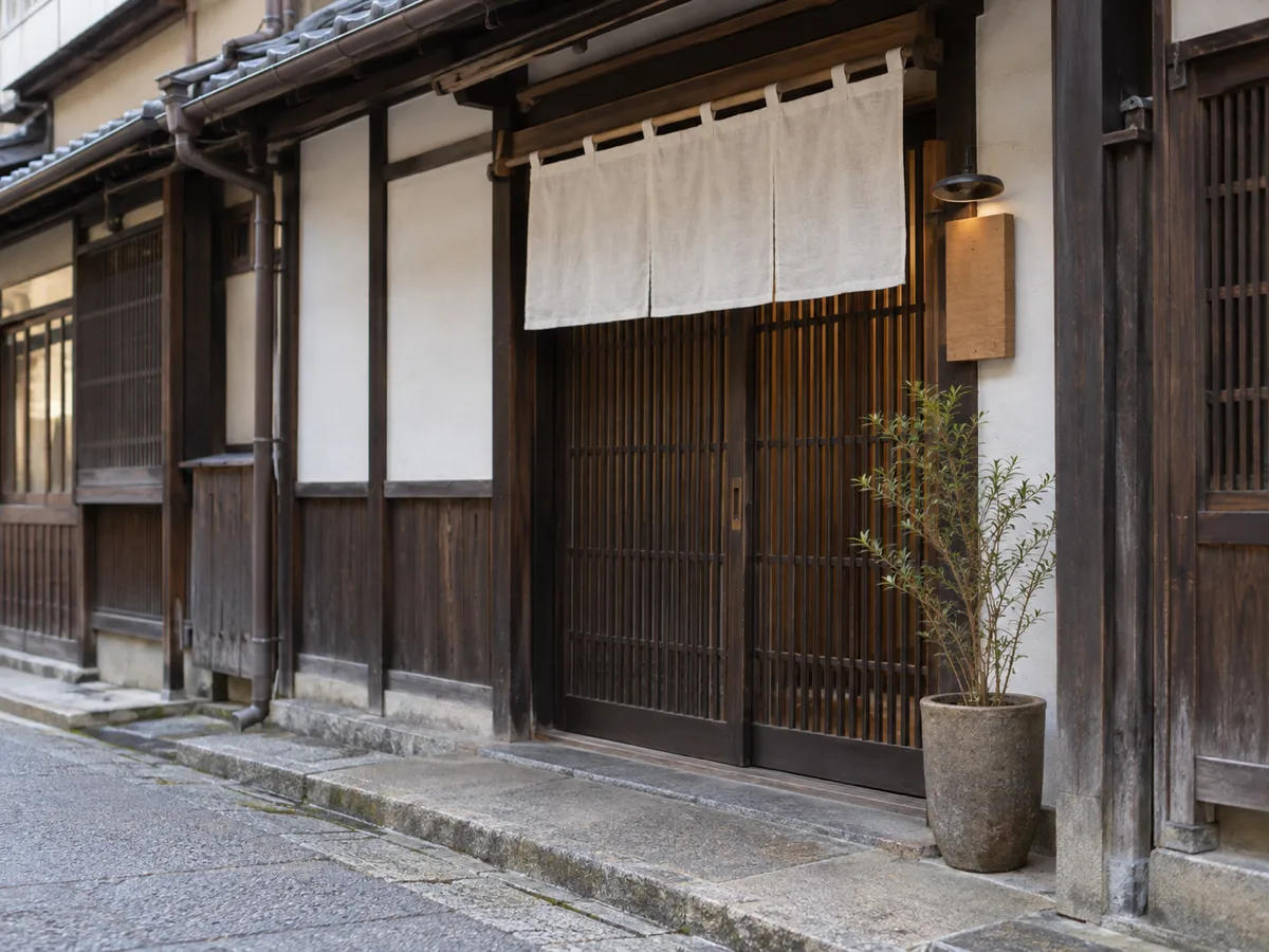 格子戸の町家の入口と、脇に掛かる小さな木の看板。